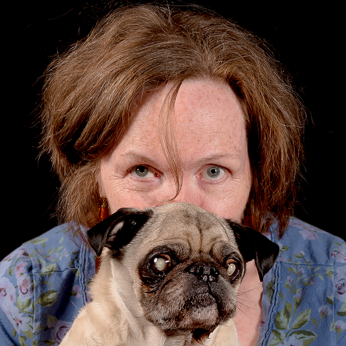 Pug and small dog owner holding a senior dog for photos